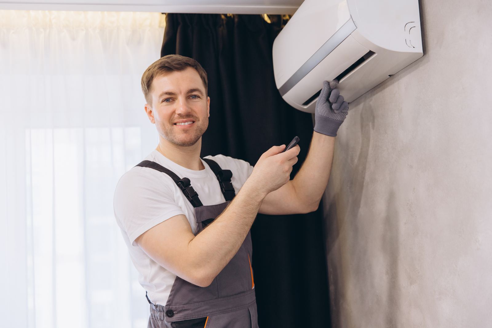 Usměvavý technik nastavuje nově namontovanou klimatizaci